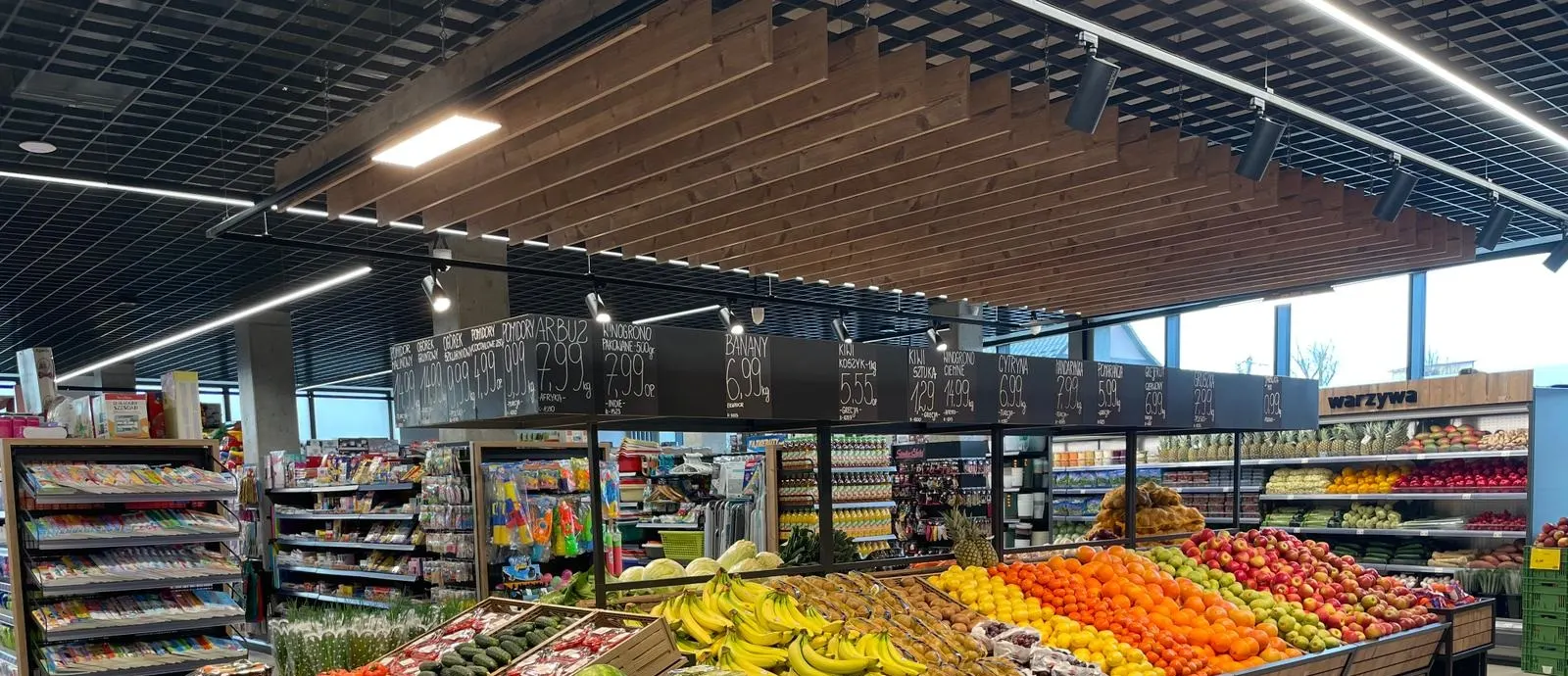 Black track spotlights and linear lights over supermarket fresh produce aisle