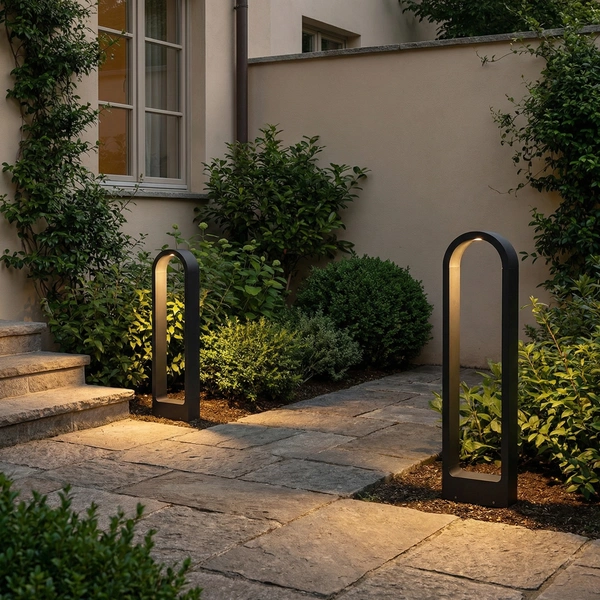 Black PORT arched bollard glowing along a garden path at dusk