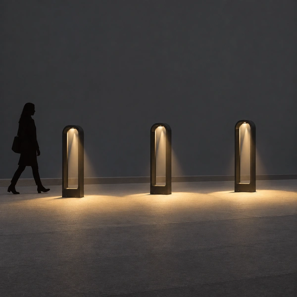 Black PORT-CO hollow arch bollards lining a stone courtyard path with touching light pools